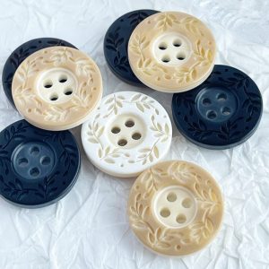 Resin 4-hole patterned buttons in cream and navy with a carved leaf wreath pattern around the four centre holes