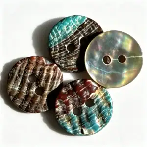 Four round abalone shell buttons with two holes, showing iridescent teal, red-brown and pearly grey shell markings