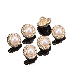 A pile of assorted mini faux pearl and rhinestone buttons with gold-tone metal in mixed decorative designs, small shank buttons for clothing and craft sewing