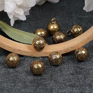Vintage brass shank buttons on a wooden tray against a dark background, brass-tone metal buttons ready for a sewing project