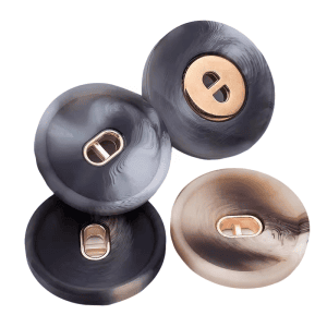 Patterned resin buttons with a gold center stacked in dark marbled and cream tones