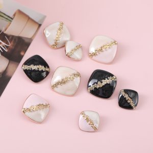 Square rhinestone enamel buttons styled on a pink background with faceted rhinestones