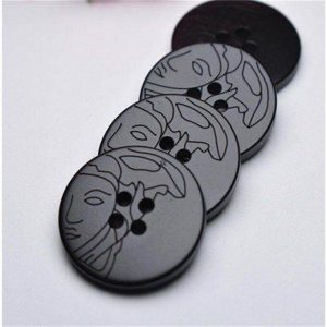 Close-up of black resin lady face buttons showing the embossed lady face design and sew-through holes