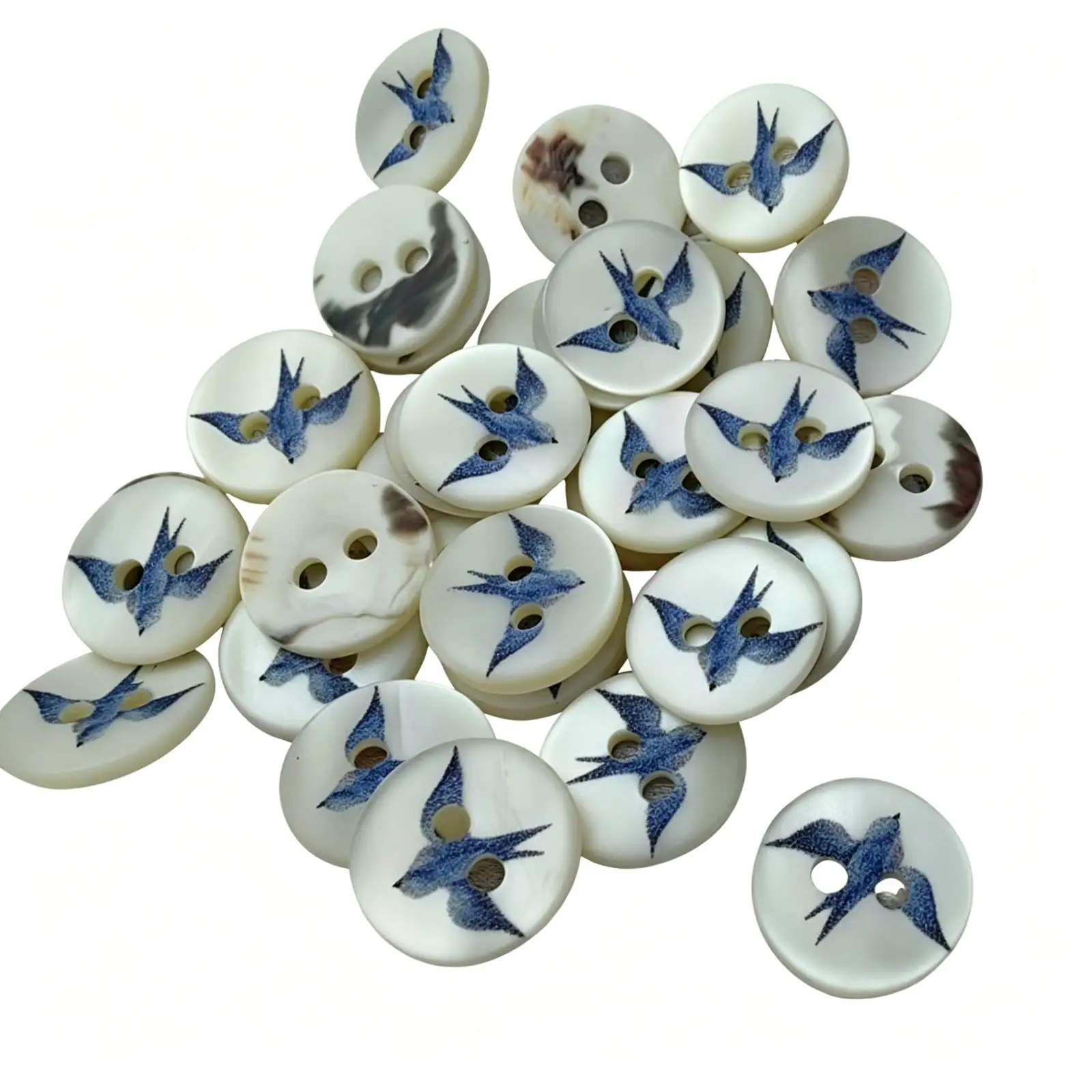 Pile of round shell buttons with two holes, each printed with a blue swallow in flight on a cream pearly face