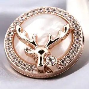 Close up of a gold-tone deer head rhinestone metal button showing the antlers, the pearly centre and the clear rhinestone ring