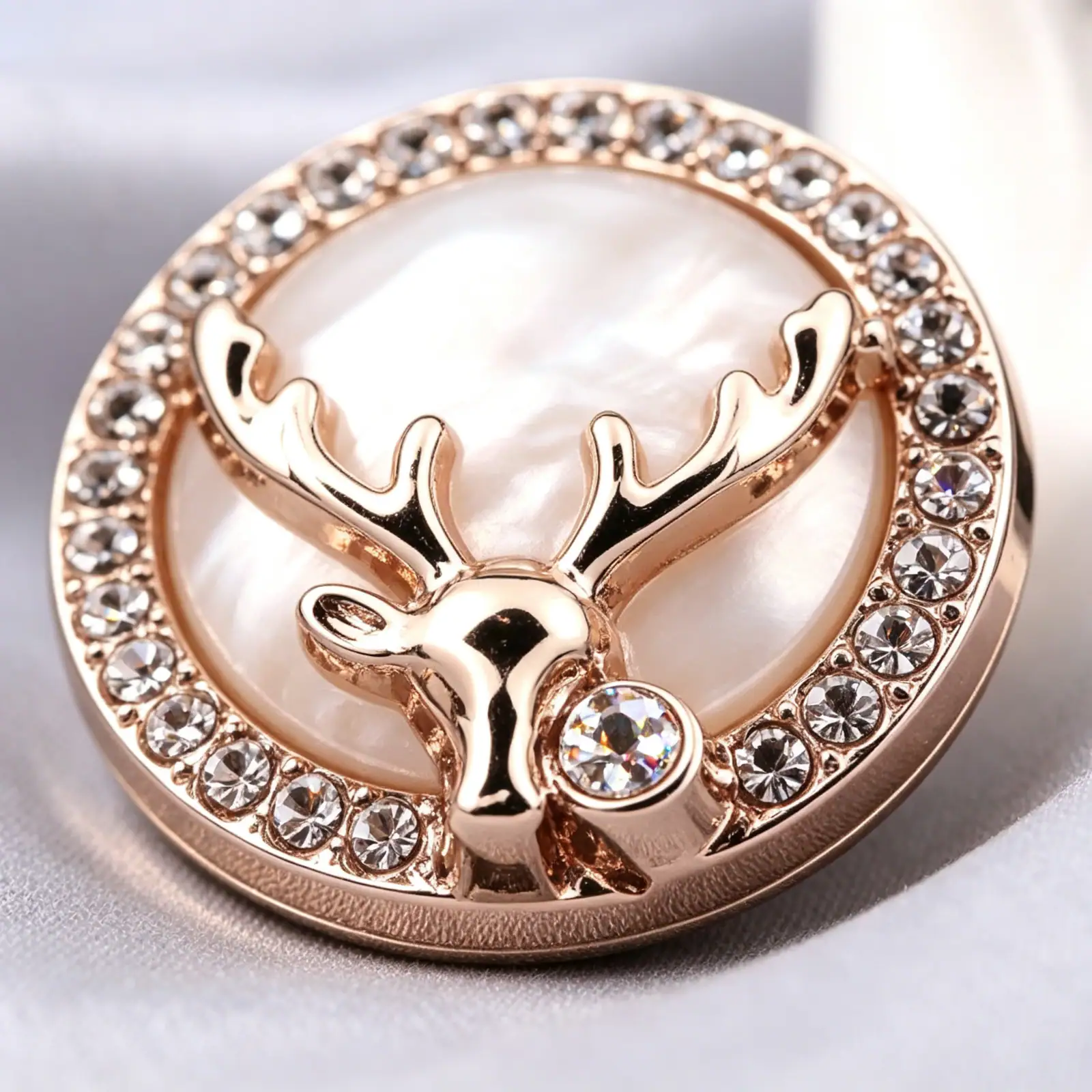 Close up of a gold-tone deer head rhinestone metal button showing the antlers, the pearly centre and the clear rhinestone ring