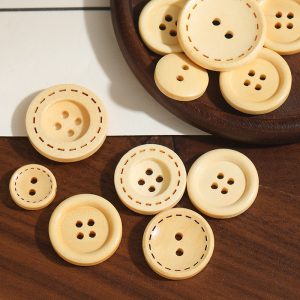 Wooden buttons in natural wood with a printed dashed stitch detail arranged on a wood surface, two-hole and four-hole sew-through buttons for sewing, knitting and DIY crafts