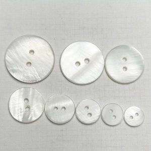 Natural white shell buttons grouped together with a striped 2-hole design in natural shell