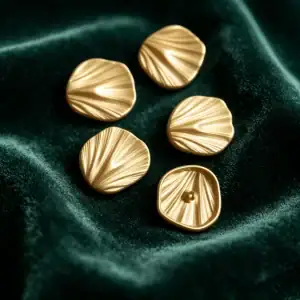 Five gold-tone ginkgo leaf buttons on dark green velvet