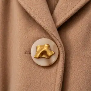 Gold metal button sewn on a camel wool coat front