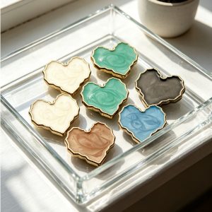 Heart enamel buttons with gold trim arranged in a tray in assorted colors
