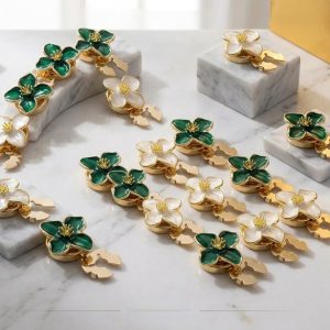 Several enamel flower button covers in cream and green with gold-tone frames and snap-on clips, no-sew flower covers
