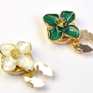 Enamel flower button covers in cream and green with a gold-tone four-petal frame and stamen center, snap-on, sold as a pair