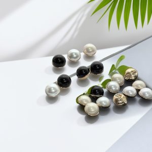 White and black faux pearl mushroom buttons styled with a green leaf, pearl-look domes