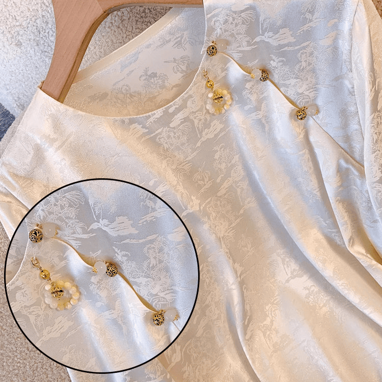 Vintage brass shank buttons with gold openwork carved ball design sewn along the neckline of a cream jacquard cheongsam-style top