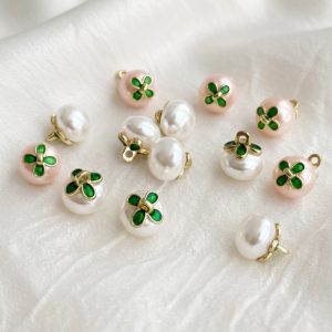 Faux pearl flower buttons with a green enamel flower on ivory and pink pearl domes and a gold-tone metal shank