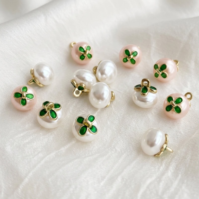Faux pearl flower buttons with a green enamel flower on ivory and pink pearl domes and a gold-tone metal shank