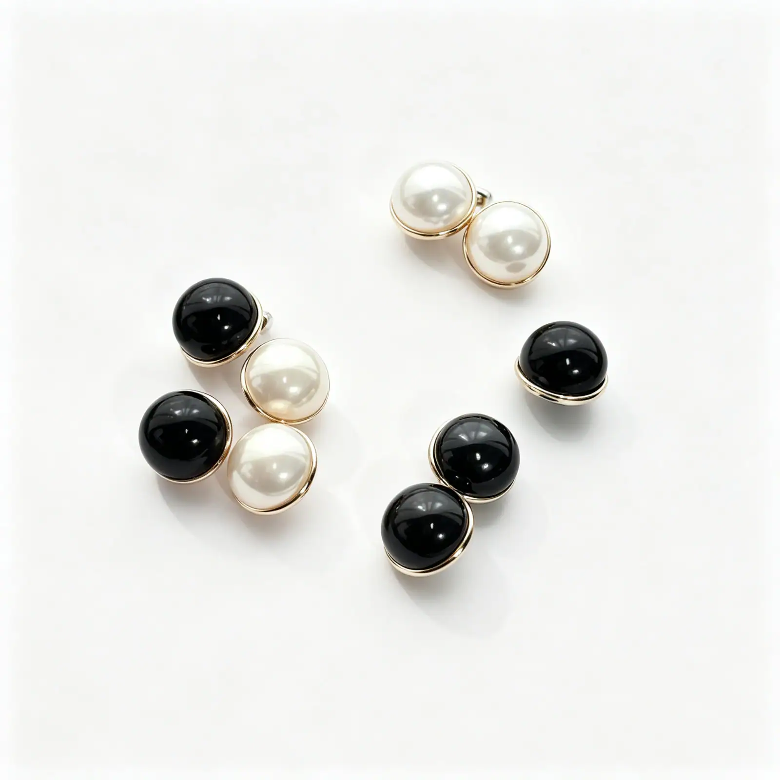 Faux pearl and black mushroom buttons with gold-tone rims on white background
