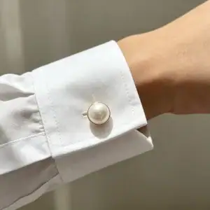 Faux pearl mushroom button fastened on a white shirt cuff