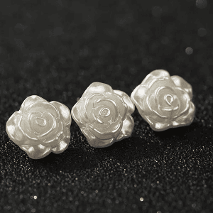 Three white faux pearl rose buttons grouped on a light background