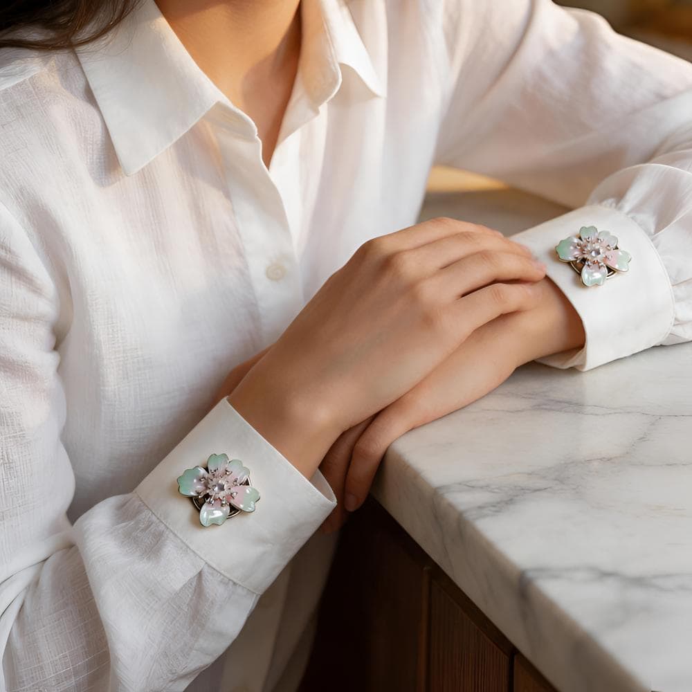 Woman wearing French cuff flower button covers on both white shirt cuffs, iridescent cyan pearl-look enamel flowers on silver-tone clips