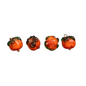 Four glass persimmon buttons in a row on a white background, handmade orange glass with green tops