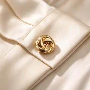 Gold-tone knot cufflink cover fastened on an ivory silk shirt cuff