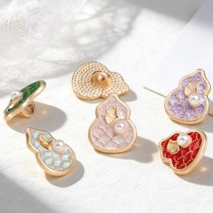 Gourd pearl metal buttons in light pink, purple, aqua blue and wine red displayed on a lace fabric surface in natural light, with one button turned over to show its textured gold-tone shank back