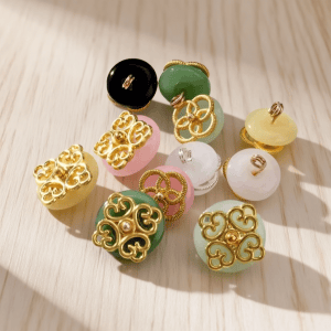 An overview of these jade filigree buttons on a white background, showing the faux jade glass domes in white, yellow, pink, green and black, each topped with openwork gold-tone metalwork. Available in an 11.5mm filigree style and a 15mm clover style for cheongsam, shirts and DIY sewing.