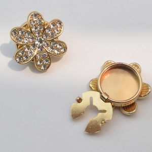 Back of a rhinestone flower button cover showing the round snap-on clip, no-sew design, with the sparkly flower front beside it