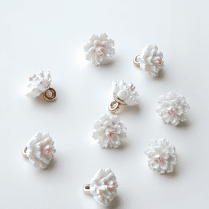 A group of white camellia flower buttons with pink centers and gold-tone shanks, floral sew-on buttons for cardigans and blouses