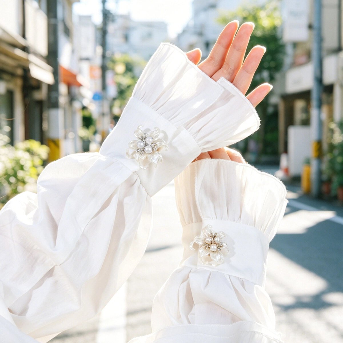 White pearl flower button decoration on white blouse cuffs