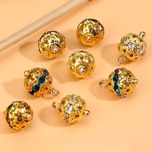 Row of gold-tone rhinestone ball buttons arranged on a soft neutral background