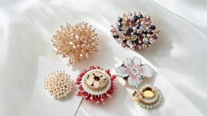 Flower cuff covers in champagne, white faux pearl, red and multicolored faceted beads, with an iridescent pearl-look enamel flower and the gold-tone clip backs