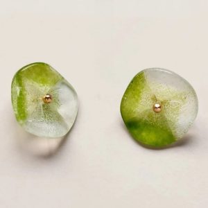 Close up of a green lotus glass button showing the frosted petal texture and the gold-tone rivet head at the centre