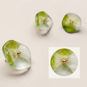 Four lotus glass buttons in translucent green with a frosted four-petal lotus face and a gold-tone rivet head at the centre