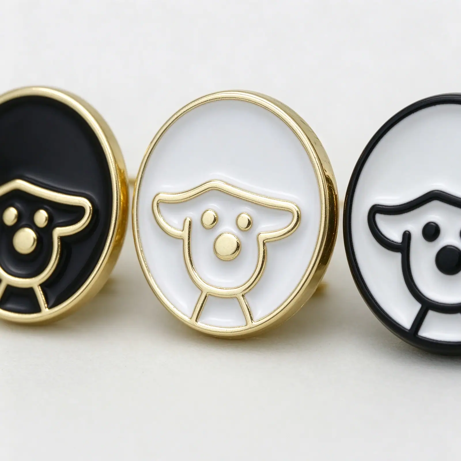 Close up of dog enamel buttons, showing the glossy enamel fill and the raised gold-tone puppy outline