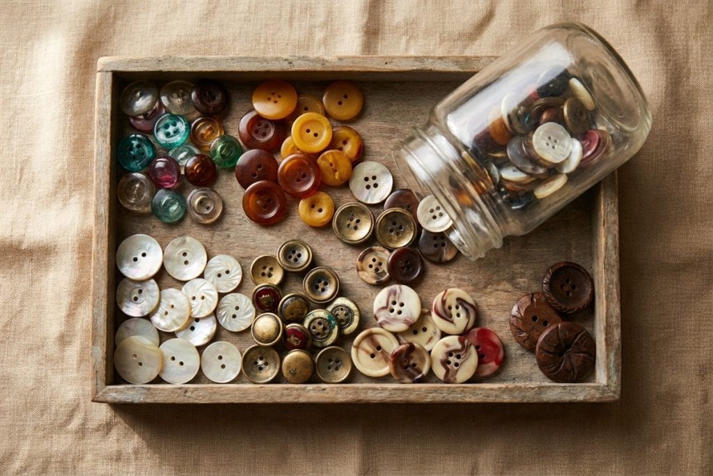 Vintage buttons in glass, Bakelite, shell and metal sorted in a wooden tray