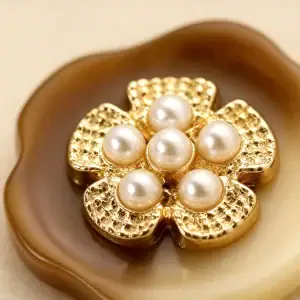 Close view of a marbled brown resin button showing its scalloped petal edge behind the gold-tone flower