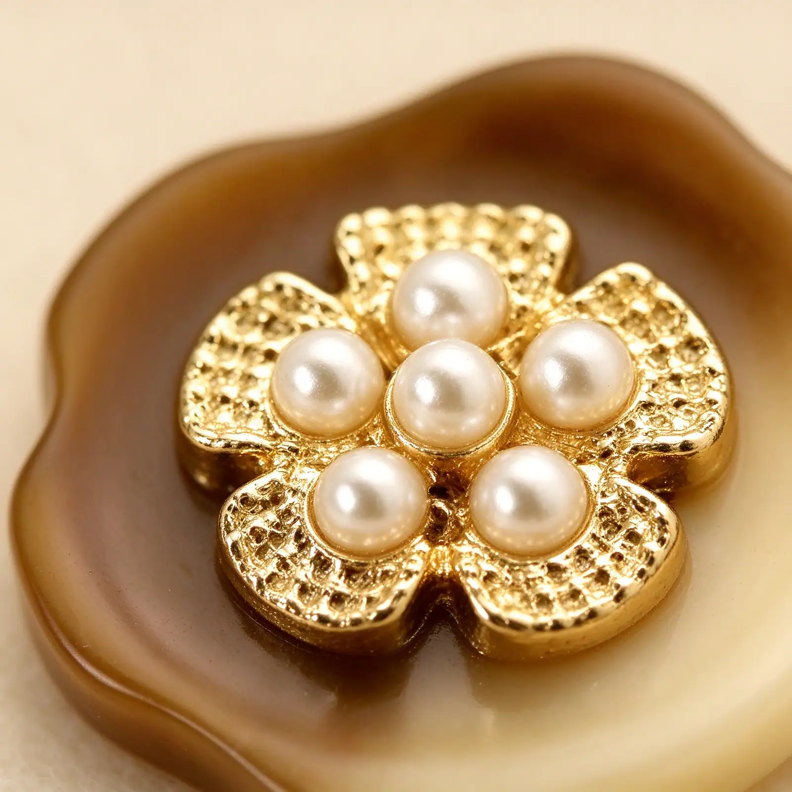 Close view of a marbled brown resin button showing its scalloped petal edge behind the gold-tone flower