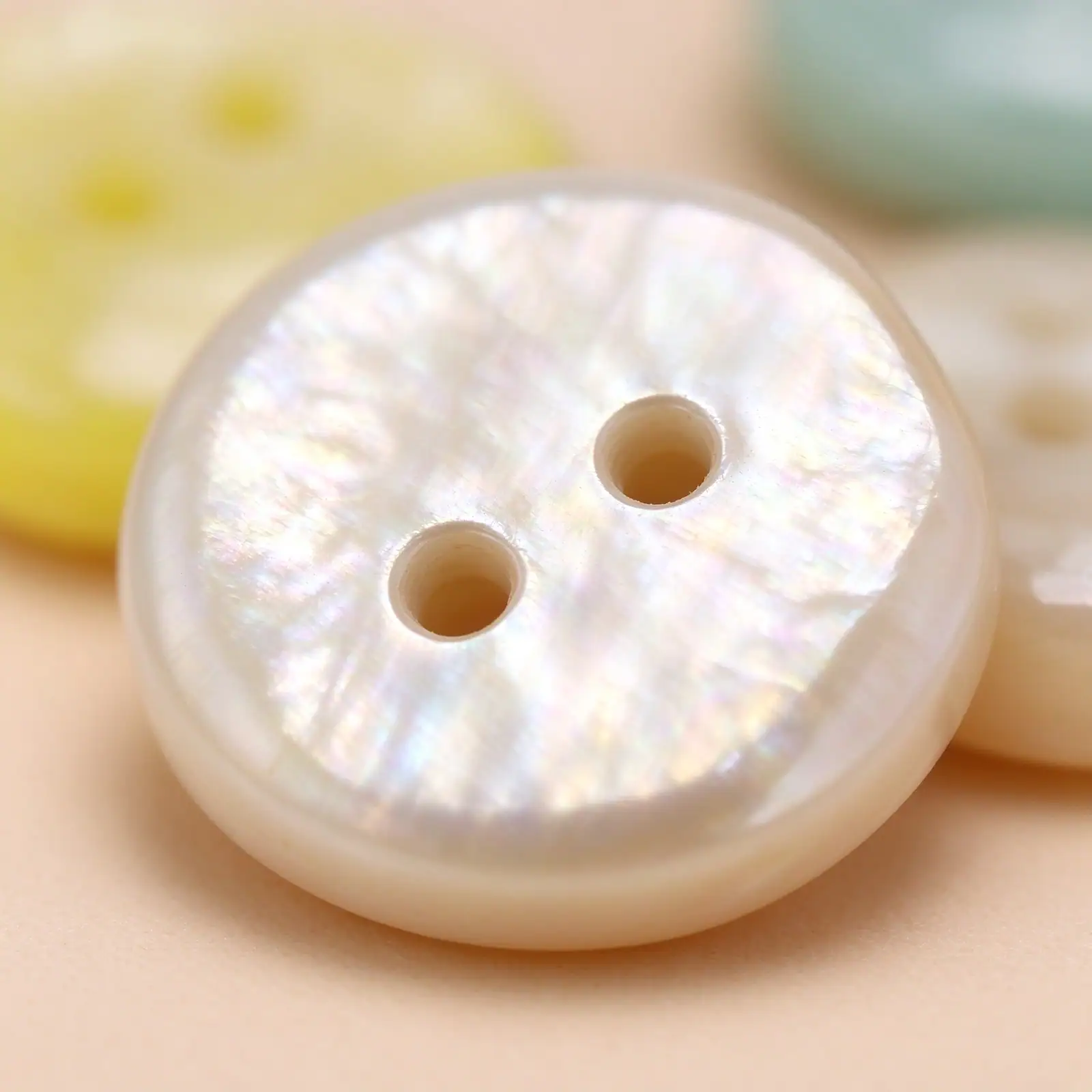 Close-up of a white resin button showing the fine pearl-look streaking moulded into the surface