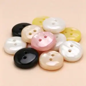 A pile of square resin buttons in black, white, cream, pink and yellow showing the pearl-look streaking on each