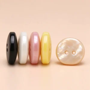 Four resin buttons standing on edge showing their thickness, with a cream button lying face up beside them