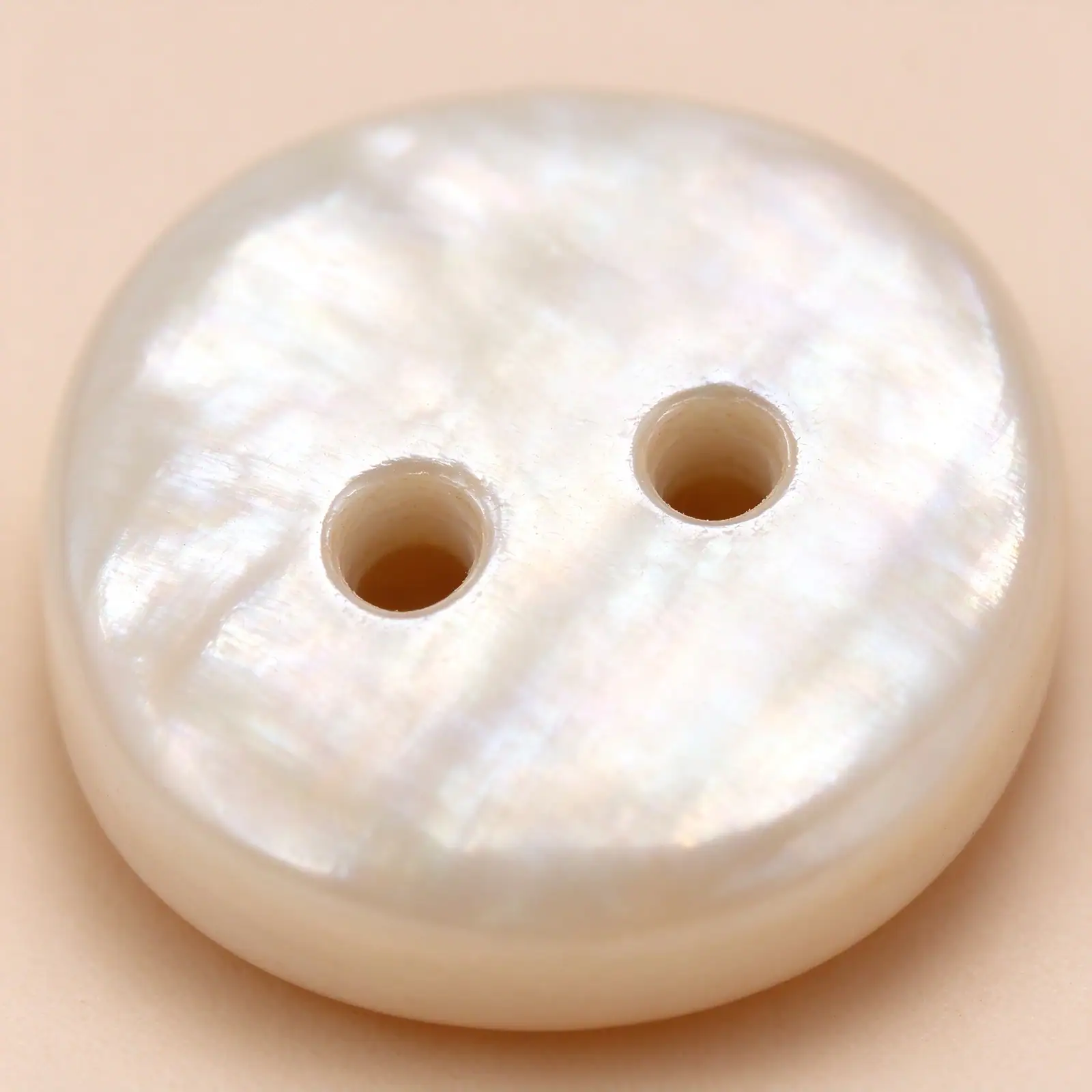 Macro view of a cream resin button showing its two centre-placed sewing holes